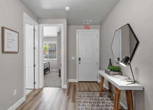 Foyer entrance with baseboards, visible vents, and light wood-style floors