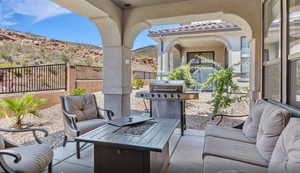 View of patio / terrace with an outdoor fire pit, a grill, fence, and a mountain view