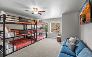 Carpeted bedroom featuring a textured ceiling, a ceiling fan, and baseboards