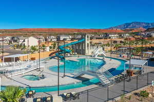 Pool with a hot tub, fence, a mountain view, a residential view, and a water slide