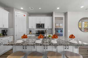 Kitchen featuring a breakfast bar, visible vents, stainless steel appliances, and white cabinets