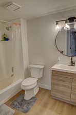 Bathroom featuring visible vents, toilet, shower / bath combo with shower curtain, vanity, and wood finished floors