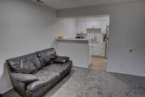 Living area with light carpet, visible vents, and baseboards