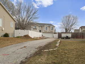 Exterior space featuring driveway, fence, and a front yard