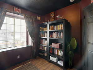 Living area with a textured ceiling, a wealth of natural light, and wood finished floors