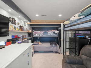 Carpeted bedroom with visible vents, a textured ceiling, and recessed lighting