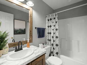 Bathroom featuring shower / bath combination with curtain, vanity, and toilet