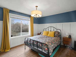 Bedroom with wainscoting, a textured ceiling, and wood finished floors