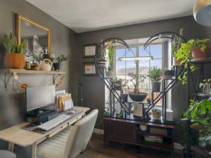 Home office with a textured ceiling, baseboards, and wood finished floors