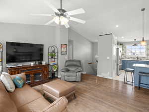 Living area with ceiling fan, light wood-style flooring, vaulted ceiling, and recessed lighting