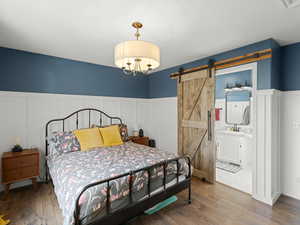 Bedroom featuring a barn door, wood finished floors, and wainscoting