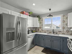 Kitchen featuring light countertops, appliances with stainless steel finishes, a sink, and white cabinetry