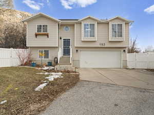 Bi-level home with entry steps, driveway, a gate, and fence