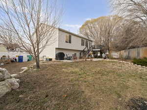 Rear view of property with a yard, a patio area, fence, a wooden deck, and stairs