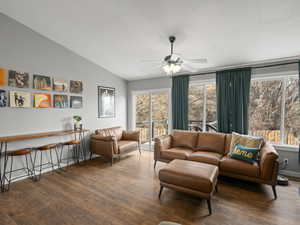 Living area with ceiling fan, a textured ceiling, vaulted ceiling, and wood finished floors