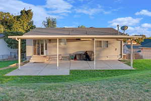 Rear view of property with roof with shingles, a lawn, a patio area, and fence