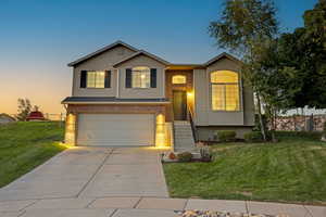 Raised ranch with driveway, an attached garage, a front yard, and brick siding