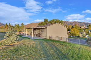 Back of property with a mountain view, a fenced backyard, a lawn, and a patio