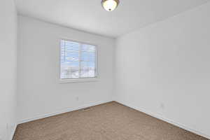 Carpeted empty room with visible vents and baseboards