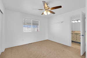 Unfurnished bedroom with a closet, visible vents, light colored carpet, ensuite bathroom, and a sink