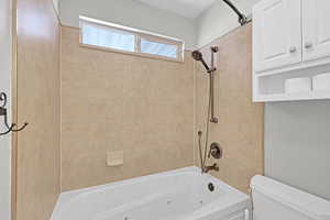 Full bathroom featuring a combined bath / shower with jetted tub and toilet