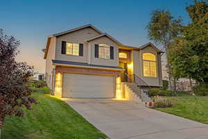 View of front of home with a garage, driveway, brick siding, and a front yard