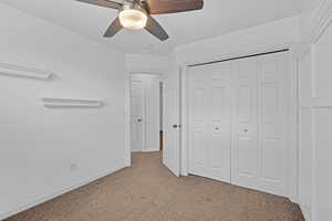 Unfurnished bedroom with a closet, light carpet, ceiling fan, and baseboards