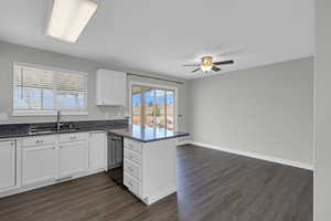 Kitchen with a peninsula, a sink, white cabinets, black dishwasher, and dark wood finished floors