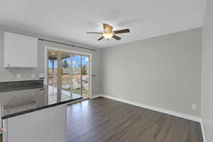 Unfurnished dining area featuring ceiling fan, dark wood finished floors, and baseboards