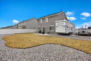 Rear view of property with cooling unit, fence, a yard, stucco siding, and a patio area