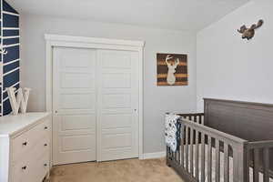 Bedroom with a closet, light carpet, and baseboards