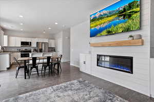 Dining space featuring recessed lighting, a large fireplace, dark wood finished floors, and baseboards