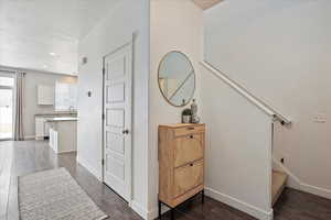 Corridor with baseboards, stairway, and dark wood-type flooring