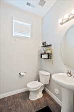 Bathroom featuring toilet, baseboards, visible vents, and wood finished floors