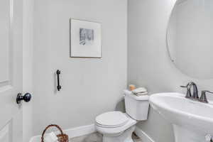 Bathroom featuring a sink, toilet, and baseboards