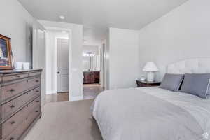 Bedroom featuring light carpet, baseboards, and connected bathroom