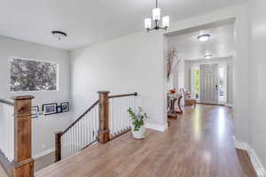 Hallway featuring visible vents, an inviting chandelier, an upstairs landing, wood finished floors, and baseboards