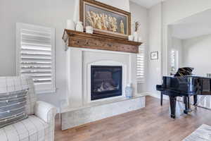 Living area featuring baseboards, wood finished floors, and a glass covered fireplace