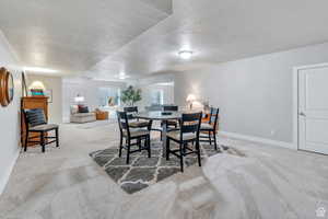 Carpeted dining area featuring a textured ceiling and baseboards