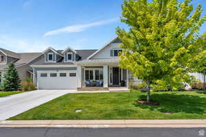 View of front facade with a front yard, a standing seam roof, metal roof, a garage, and driveway