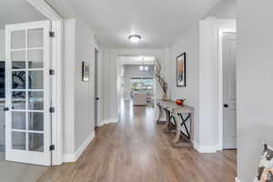 Hallway featuring light wood-type flooring, baseboards, and a notable chandelier