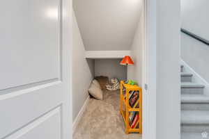 Interior space with a textured ceiling, baseboards, vaulted ceiling, and carpet flooring