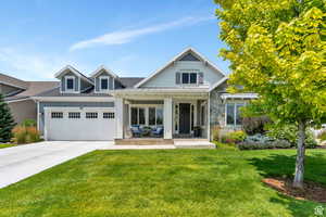 View of front of property with a garage, driveway, covered porch, a standing seam roof, and a front lawn