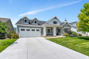 View of front of house featuring a garage, driveway, roof with shingles, covered porch, and a front lawn