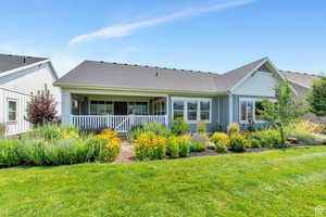 Rear view of property with a shingled roof, covered porch, and a yard