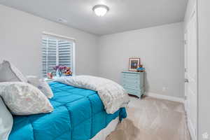 Bedroom featuring light carpet, a textured ceiling, visible vents, and baseboards