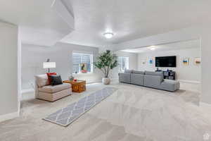 Living area featuring carpet flooring, a textured ceiling, and baseboards