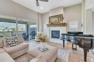 Living room featuring a glass covered fireplace, wood finished floors, a ceiling fan, and recessed lighting