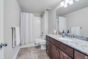 Bathroom featuring visible vents, toilet, shower / bath combo with shower curtain, vanity, and baseboards