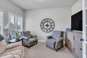 Living area featuring light colored carpet and baseboards